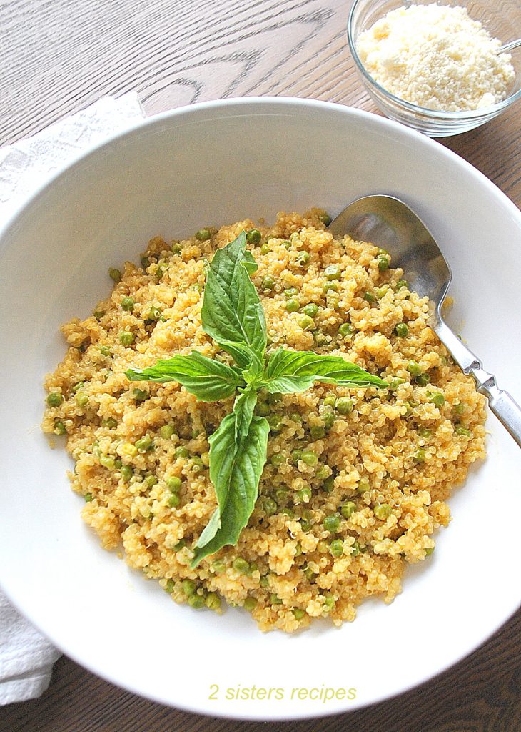 A white bowl filled with cooked quinoa with baby peas.