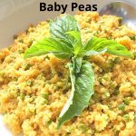 A white bowl filled with cooked quinoa with baby peas and fresh basil leaves on top.