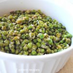 A white bowl filled with sautéed baby peas and onions.