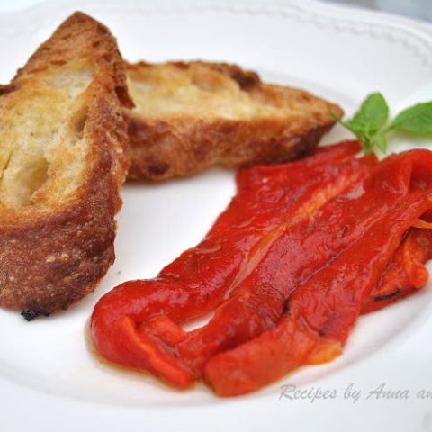 Roasted Red Bell Peppers served on a white plate with sliced toasted bread on the side.