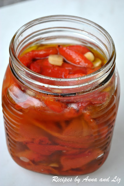 A mason jar filled with roasted red peppers, olive oil and fresh garlic. 