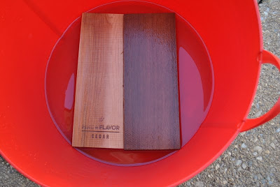 Cedar planks soaking is a red bucket filled with water. 