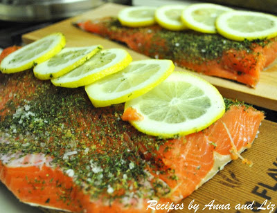 Raw salmon, seasoned with lemon slices on top sitting on cedar planks. by 2sistersrecipes.com