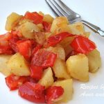a white plate with a serving of roasted potatoes and chopped red peppers.