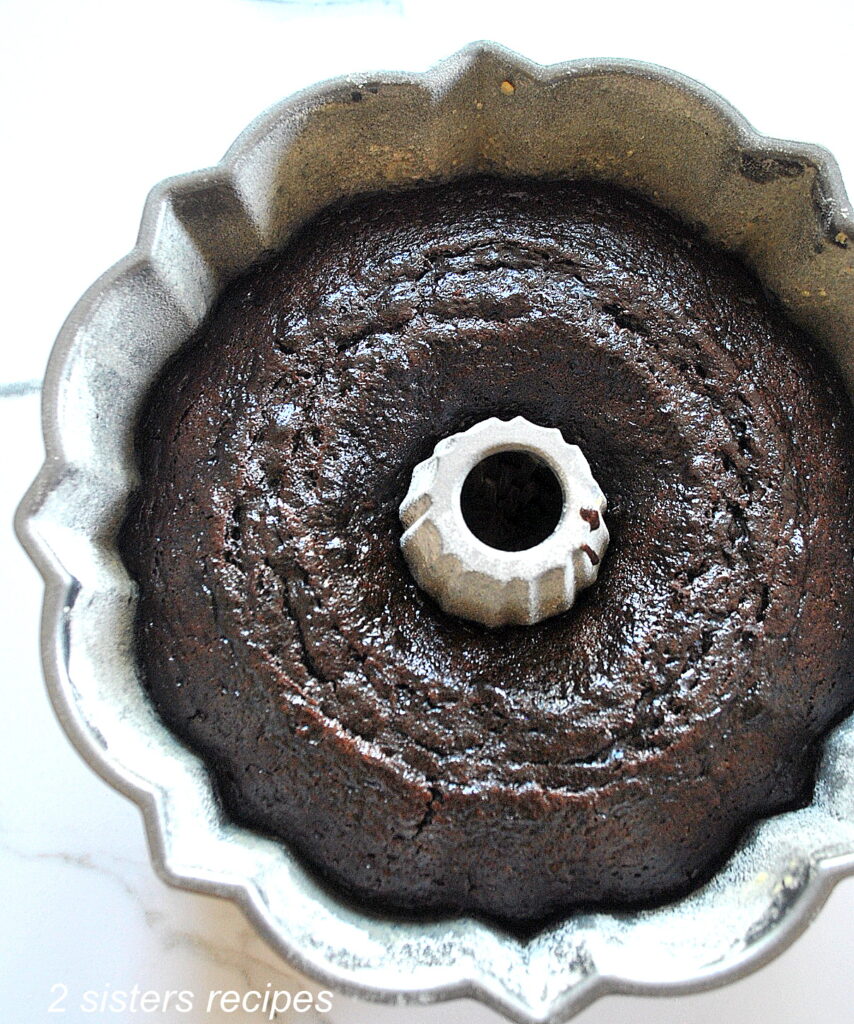 A fully baked chocolate cake cooling in a Bundt Cake pan.