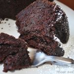 A forkful of chocolate cake served on a white plate.