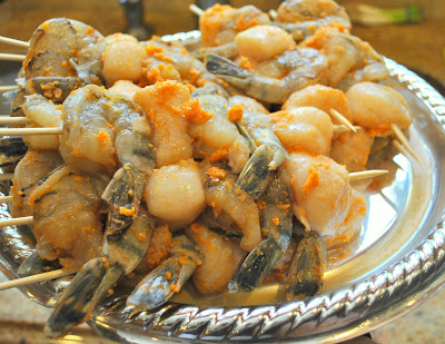 Shrimps and Scallops kabobs on a platter with marinade over them. by 2sistersrecipes.com 