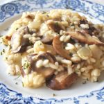 Risotto con Funghi (Mushrooms) is served on a white and blue plate.