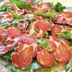 Capocollo thinly sliced and served over a bed of arugula leaves topped with capers.