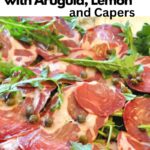 Thinly sliced cured Italian meat, called capocollo served with arugula leaves and capers.