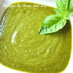 A white bowl filled with freshly made basil pesto sauce with a fresh basil as garnish.