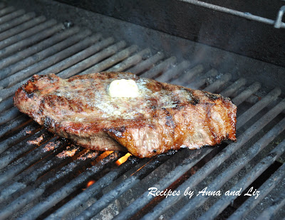 Steak on an outside grill with some butter on top.