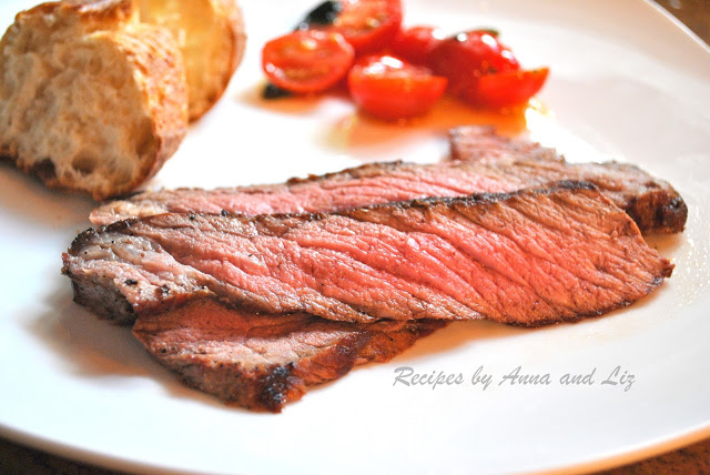 London Broil Steak sliced and served on a white plate with bread, and tomatoes.