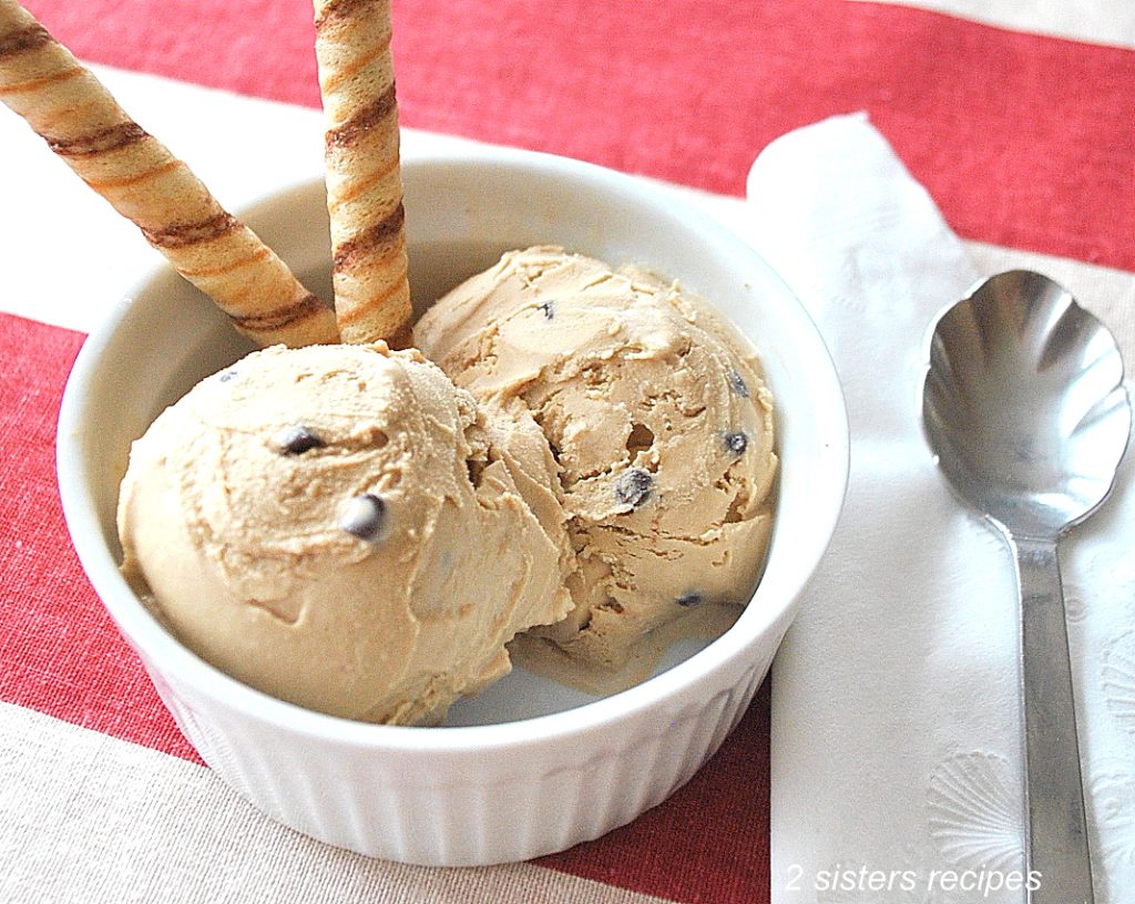 Two scoops of ice cream serving in a small ramekin with 2 swirl cookies. 