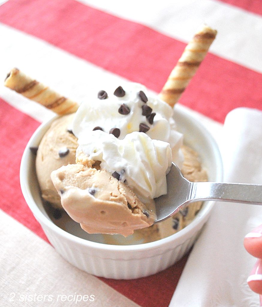 A spoonful of coffee flavored ice cream with whipped cream.
