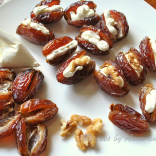 Dates filled with cheese, and walnuts on a white plate. by 2sistersrecipes.com