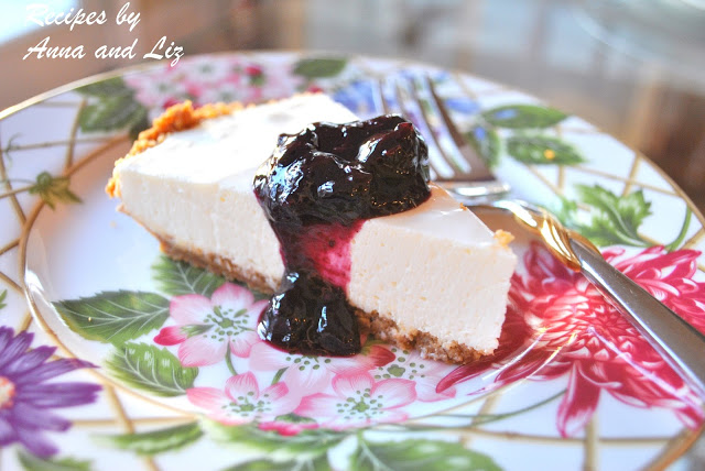 A slice of pie with blueberry sauce on top on a colorful plate. by 2sistersrecipes.com