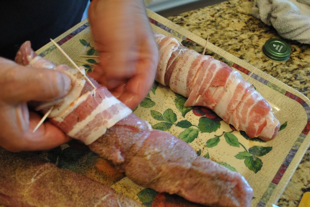 Bacon is being wrapped around each tenderloin and held with toothpicks. by 2sistersrecipes.com