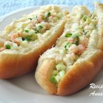 Two hotdog rolls filled with lobster and shrimp salad, served on a white plate.