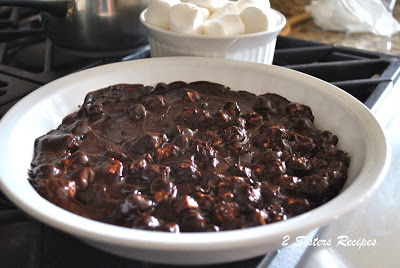 Melted chocolate mixture is poured into a white round baking dish. by 2sistersrecipes.com 