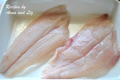 2 pieces of raw white skinless fish laid inside a white baking dish. 