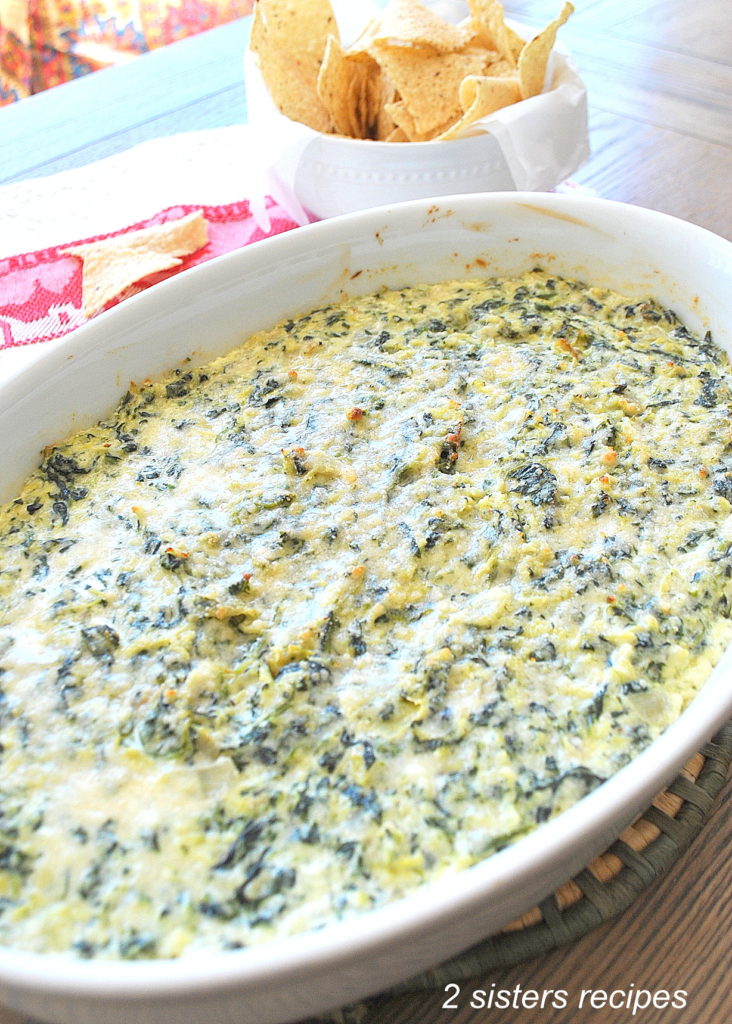 A white platter filled with spinach and artichoke dip baked.