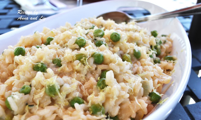 A white oval bowl filled with cooked Italian rice and baby peas.