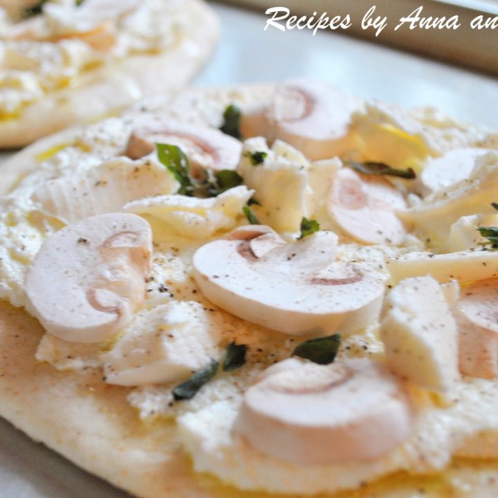A pita bread topped with raw sliced mushrooms and fresh herbs and ricotta cheese.