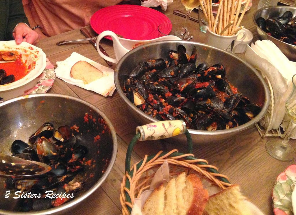 A bowl filled with mussels at a dinner table.
