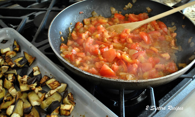 A skillet sautéing on stovetop chopped tomatoes. by 2sistersrecipes.com 