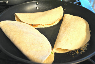 3 flat tortillas folded over in a black skillet on stovetop/. by 2sistersrecipes.com