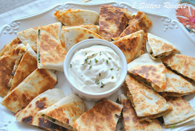 A large platter with quesadillas and a small bowl of sour cream for dipping. by 2sistersrecipes.com 