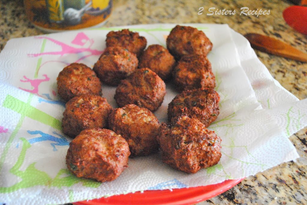  A bunch of fried meatballs draining on  paper towels, before going into the pot of sauce. by 2sistersrecipes.com