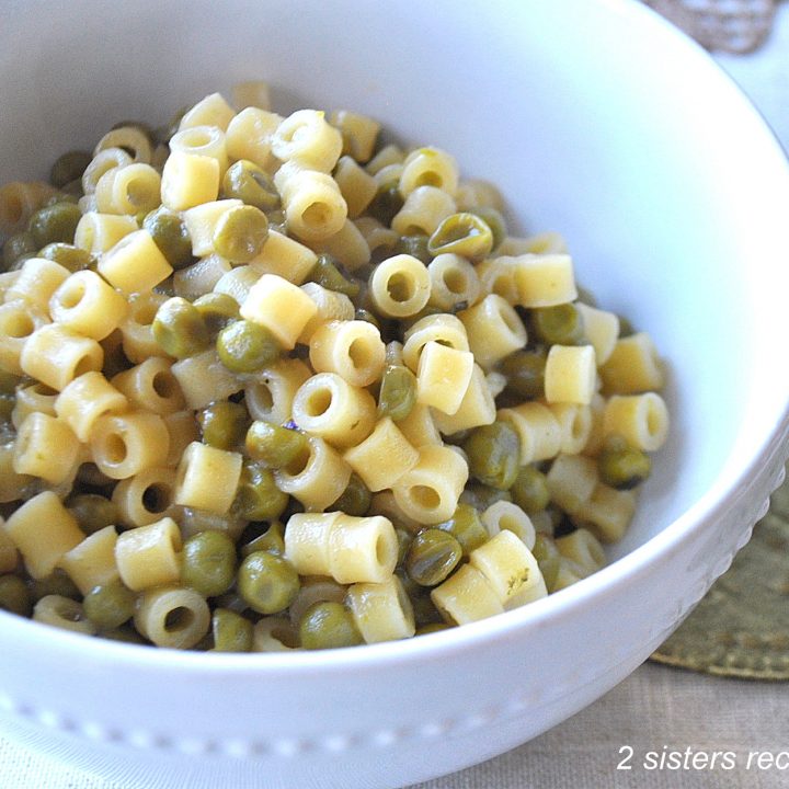 A white bowl filled with little pasta and peas.