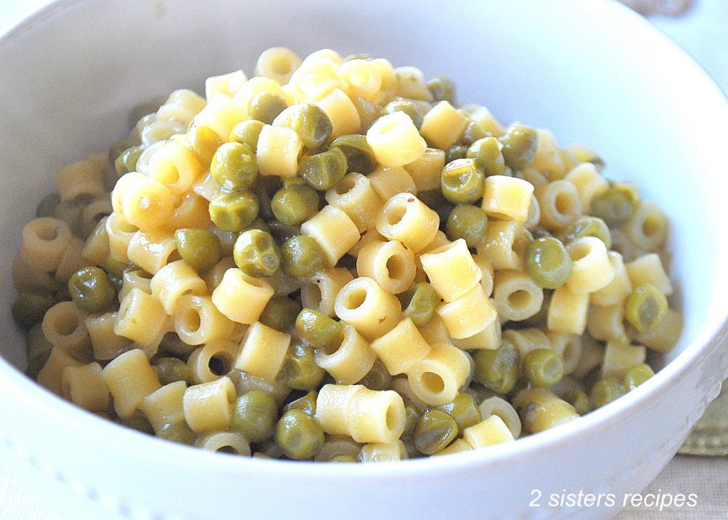 A white bowl filled with baby pasta and peas.