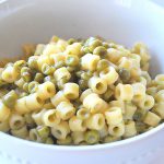 A white bowl filled with small pasta and baby peas.
