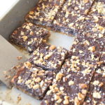A baking pan filled with dark chocolate bars topped with crushed nuts.