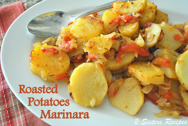 A serving platter with roasted potatoes with tomatoes and seasonings.