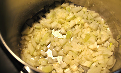 A large pot with raw onions cooking.