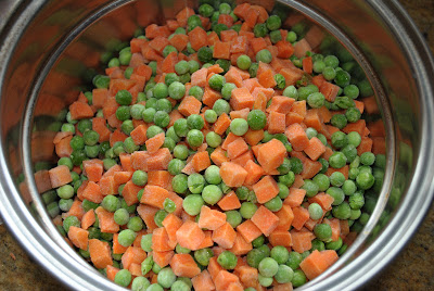 A pot filled with frozen mix of peas and chopped carrots.