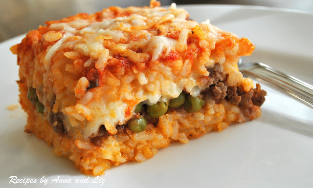 On a white plate is a serving of rice casserole stuffed with meat , peas and melted cheese in the center. 