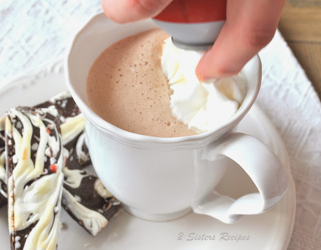 Adding whipped cream to the latte. by 2sistersrecipes.com 