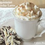 A white mug with whipped cream and a side of peppermint chocolate cookies.