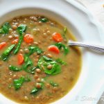 A bowl of lentil soup with spinach in it.