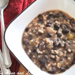 A bowl of soup with spoons on a red napkin.