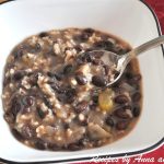 A bowl of a beans and rice soup with a spoon.