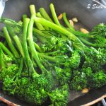 A black skillet filled with fresh broccolini.