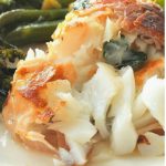 Easy Cod Saltimbocca is served on a white plate with broccolini next to it.