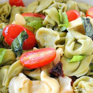 A mixture of cheese tortellini pasta with cherry tomatoes.