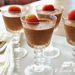 Four cordial glasses filled with chocolate mousse, topped with a strawberry.